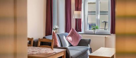 Un salon avec un canapé, une table et une fenêtre avec des rideaux.