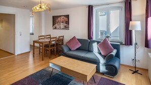 Uma sala de estar moderna com sofá, mesa de centro e conjunto de jantar.