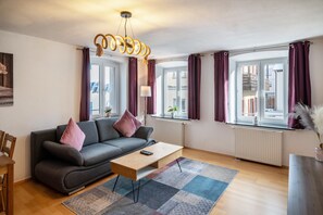 A modern living room with a sofa, a coffee table, and a chandelier.