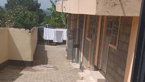 A paved courtyard with a building featuring a balcony and a window with a decorative frame. - Hillview Heights Haven Guest & Hotel (Webuye)