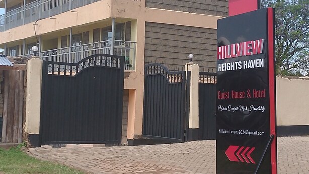A multi-story building with balconies, a black gate, and a signboard advertising Hillview Heights Haven as a guest house and hotel. - Hillview Heights Haven Guest & Hotel (Webuye)