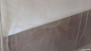 A single bed with a white sheet and a pillow, a mosquito net above, and a wooden headboard. - Hillview Heights Haven Guest & Hotel (Webuye)