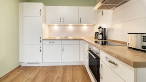 Eine moderne Küche mit weißen Schränken, einer Holzauskładung, einem Einbauofen und einem Toaster.