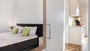 Un dormitorio con cama, mesita de noche y vistas a una cocina.
