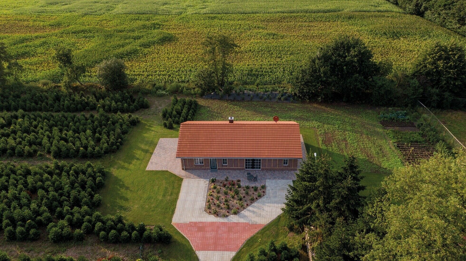 Une maison avec un toit rouge, entourée d’une pelouse bien entretenue et d’un jardin.