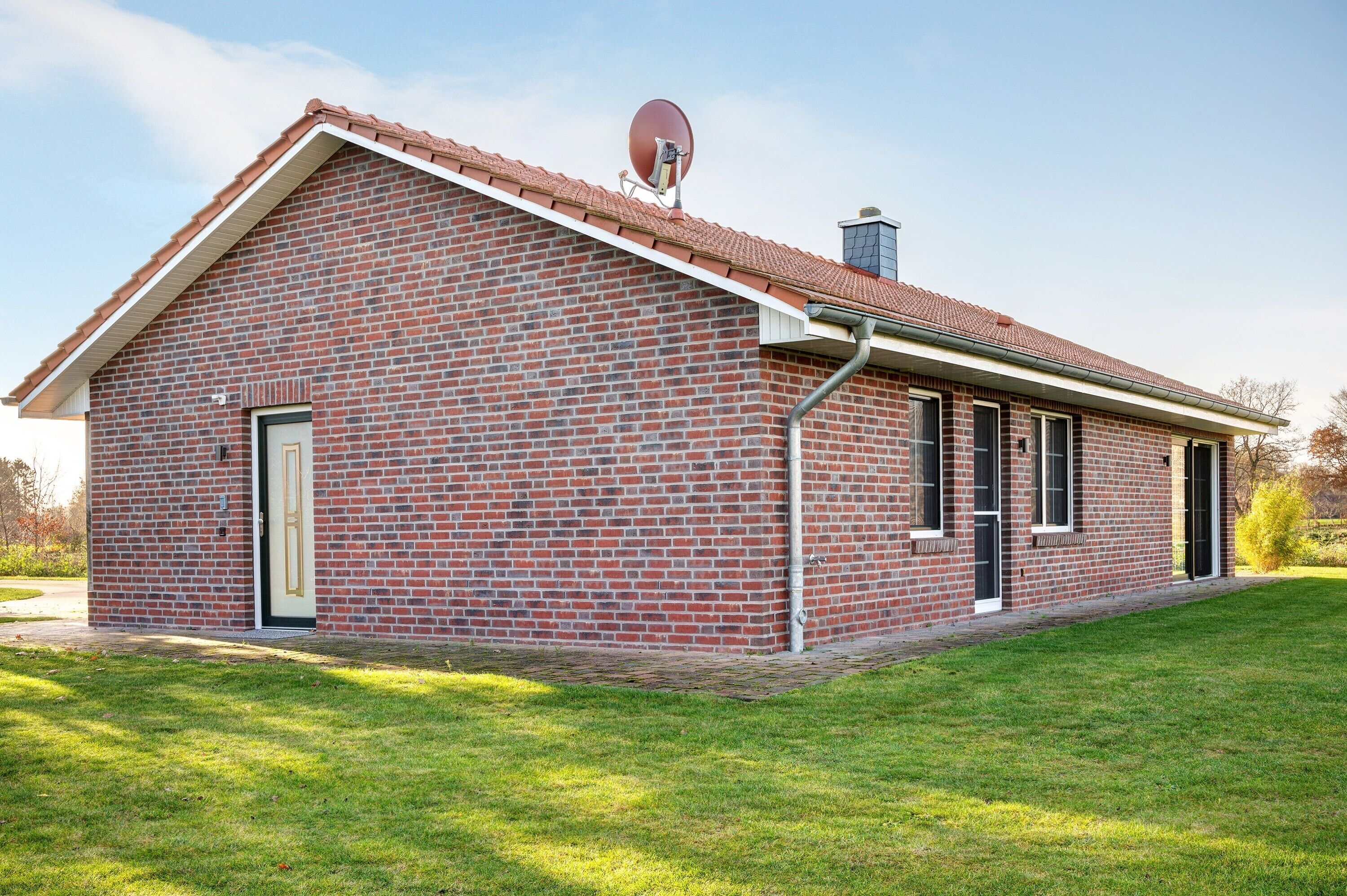 Een gebouw van baksteen met een schuin dak, een schotelantenne en een schoorsteen.