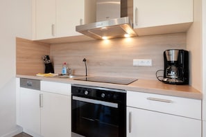 Eine moderne Küche mit Geschirrspüler, Backofen, Kaffeemaschine und Holzarbeitsplatte.