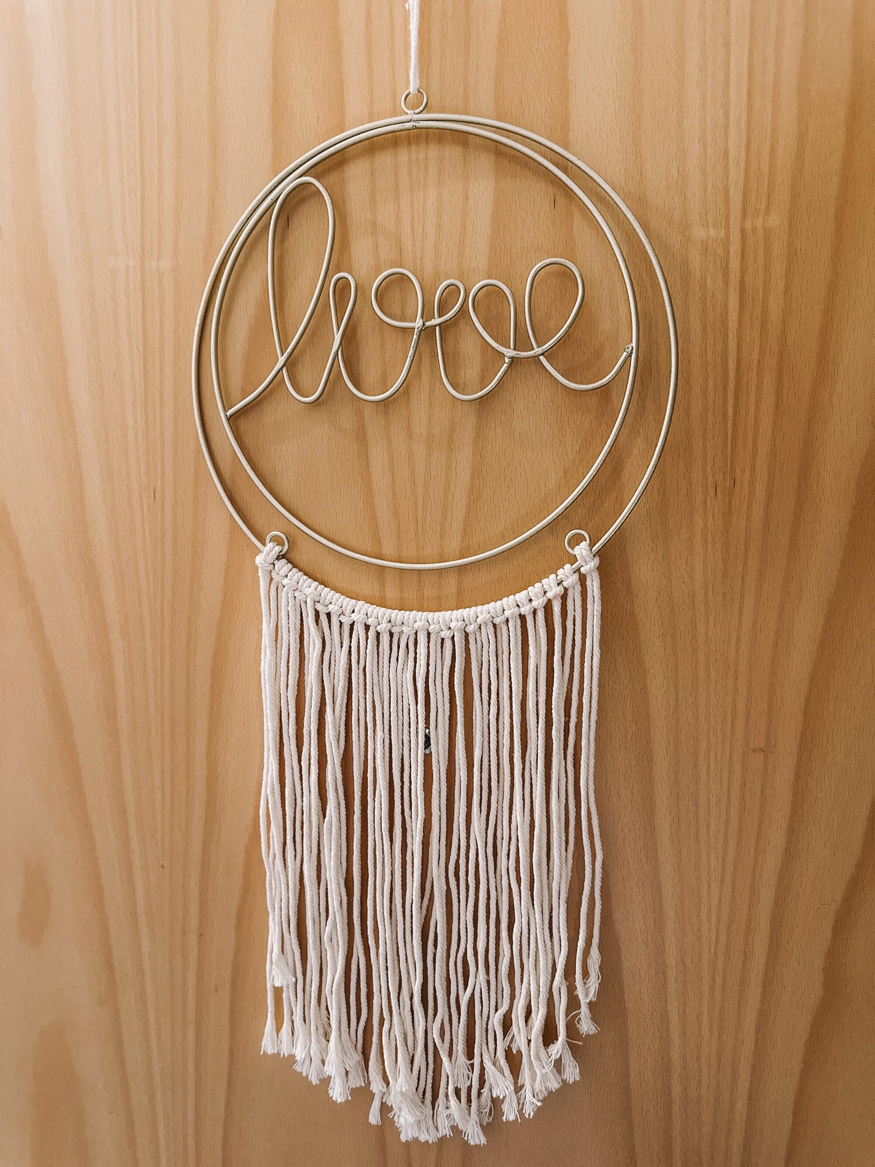 Un tapiz de macramé con la palabra 'love' y un marco circular.