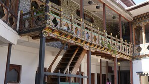 A traditional building with a balcony, stone flooring, and a staircase. - Kingaling Hotel (Punakha)