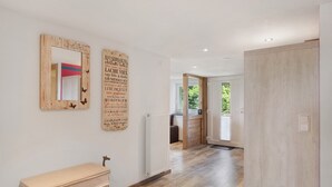 A hallway with wooden flooring, a radiator, a wooden cabinet, and two wall-mounted mirrors with text. - Apartment Zwergenschlössle with Private Garden and Wi-Fi (Breitnau)