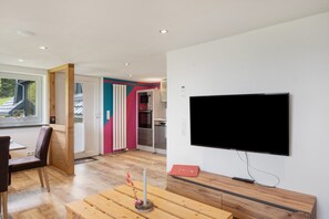 Un salon moderne doté d’un téléviseur à écran plat, de meubles en bois et offrant une vue sur l’extérieur.