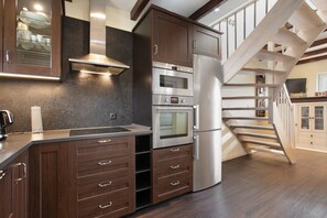Una cocina moderna con electrodomésticos integrados, una escalera de madera y vistas al salón.