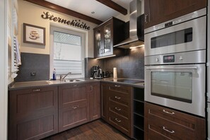 Una cocina moderna con armarios de madera oscura, electrodomésticos de acero inoxidable y una decoración de pared con tema de café.