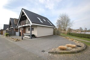 Ein modernes Haus mit einem geneigten Dach, einem Balkon und einer gepflasterten Auffahrt.