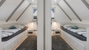 Une vue en miroir d’une chambre à coucher avec un lit en mezzanine, des tables de chevet et une fenêtre.