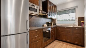Une cuisine moderne dotée d’appareils électroménagers en acier inoxydable, de meubles en bois et d’une grande fenêtre.
