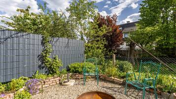 Ein Garten mit einem Metallstuhl, einer Schubkarre und einer Mauer aus Ziegelsteinen.