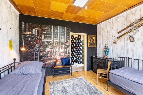 A room with two beds, a bench, a wall of records, and a ski rack.
