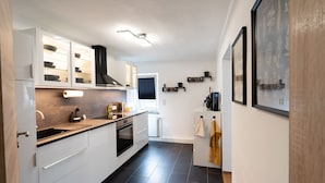 A modern kitchen with white cabinets, a black countertop, and a built-in oven. - Apartment 'Ferienwohnung Sunny' with Mountain View and Wi-Fi (Schmallenberg)