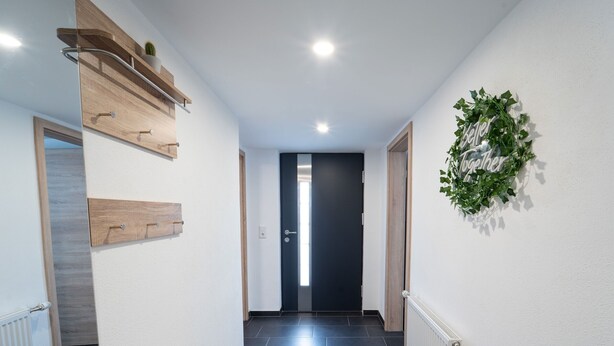 A hallway with a wooden bench, a radiator, a door, and a wall-mounted plant. - Apartment 'Ferienwohnung Sunny' with Mountain View and Wi-Fi (Schmallenberg)