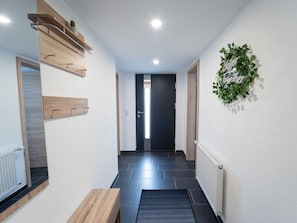 A hallway with a wooden bench, a radiator, a door, and a wall-mounted plant. - Apartment 'Ferienwohnung Sunny' with Mountain View and Wi-Fi (Schmallenberg)