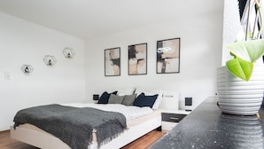 A modern bedroom with a bed, bedside tables, a nightstand, a potted plant, and abstract wall art. - Apartment 'Ferienwohnung Sunny' with Mountain View and Wi-Fi (Schmallenberg)