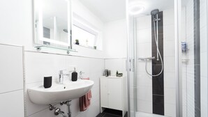 A modern bathroom with a white sink, mirror, and glass shower enclosure. - Apartment 'Ferienwohnung Sunny' with Mountain View and Wi-Fi (Schmallenberg)