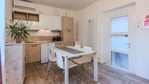 Een moderne keuken met witte kasten, een eettafel met stoelen en een inbouwoven.
