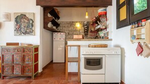 A compact kitchen with a refrigerator, oven, and hanging baskets.