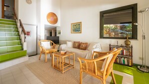 A living room with a sofa, two armchairs, a coffee table, a bookshelf, a television, and a staircase with green steps. - Lovely apartment for 7 guests with WIFI, TV and terrace (Quartu Sant'elena)