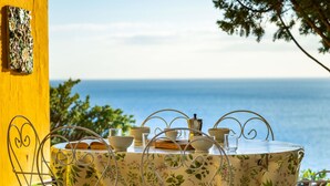 A table set with tea cups and saucers, a teapot, and a sugar bowl, overlooking a body of water. - Lovely apartment for 7 guests with WIFI, TV and terrace (Quartu Sant'elena)