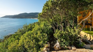 A coastal property with a view of the sea, surrounded by lush greenery and a Mediterranean-style building. - Lovely apartment for 7 guests with WIFI, TV and terrace (Quartu Sant'elena)