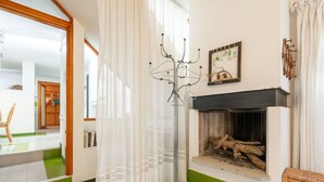 A living room with a fireplace, a coat rack, and a green-tiled floor. - Lovely apartment for 7 guests with WIFI, TV and terrace (Quartu Sant'elena)