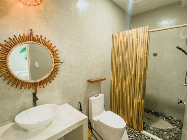 Un baño con un espejo redondo, dos lavamanos, un inodoro y una zona de ducha con paneles de bambú.