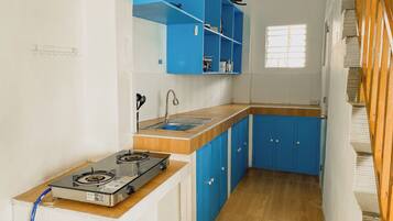 A compact kitchen with blue cabinets, a gas stove, and a window providing natural light.