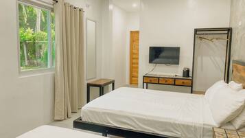A modern hotel room with a large bed, a TV, a bedside table, and a window with curtains.