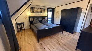 A bedroom with a bed, a desk, a wardrobe, and a sloped ceiling. - Holiday Apartment Herzogenhorn with Mountain View, Private Terrace and Wi-Fi (Bernau im Schwarzwald)