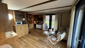 A wooden interior with a kitchen, dining area, and a seating area with a view of the outdoors. - Holiday Apartment Herzogenhorn with Mountain View, Private Terrace and Wi-Fi (Bernau im Schwarzwald)