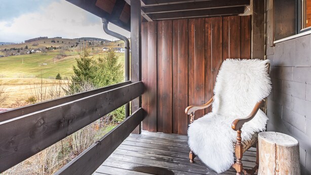 A wooden porch with a bench and a chair, overlooking a rural landscape. - Holiday Apartment Herzogenhorn with Mountain View, Private Terrace and Wi-Fi (Bernau im Schwarzwald)