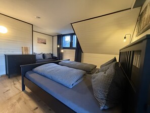 Un dormitorio moderno con cama, mesitas de noche, un escritorio y una ventana.