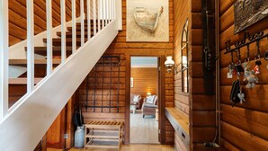 A wooden interior with a staircase, a bench, a fireplace, and a wall-mounted key rack.