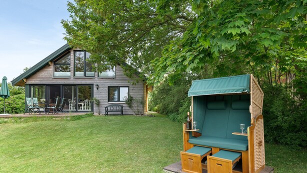 A modern house with a deck, a green outdoor seating area, and a well-maintained lawn. - Holiday Home Schleiblick with Barrel Sauna, Private Terrace and Wi-Fi (Ulsnis)