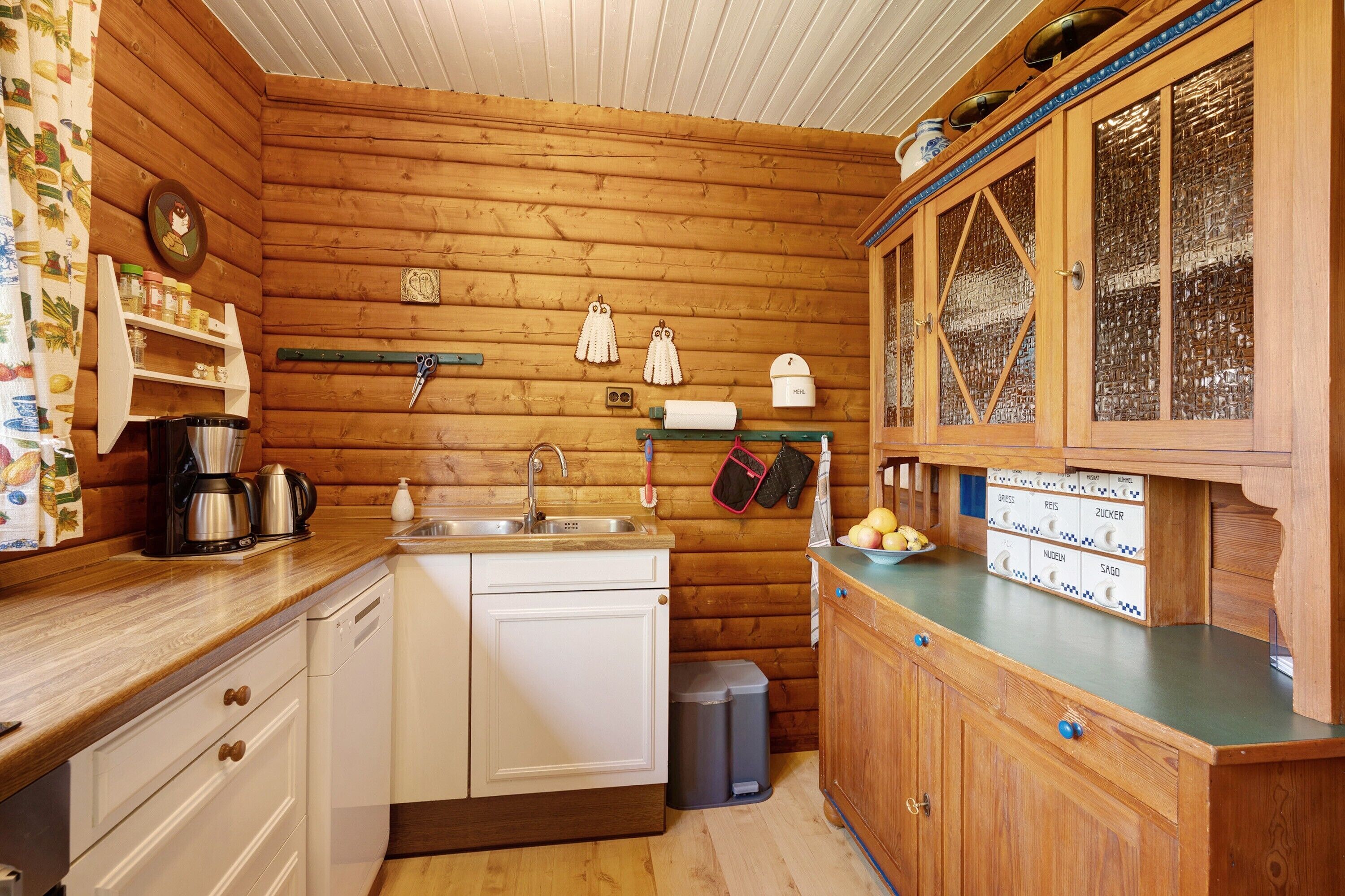 Cocina de cabaña de madera con lavamanos, armarios y cafetera.