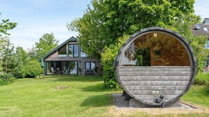A house with a large wooden barrel structure in the front yard.