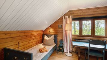A bedroom with a sloped ceiling, a wooden bed, a desk, and a chair.