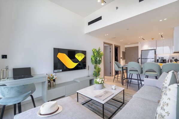 A modern living room with a sofa, coffee table, and a TV mounted on the wall. - Vogue | Binghatti Corner JVC near Circle Mall (Dubai)
