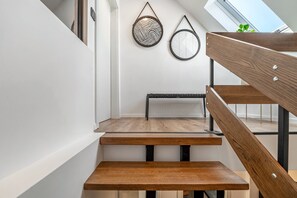 En moderne trappe med trætrin og metalgelændere, der fører til en platform med en bænk.