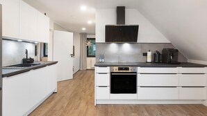 Een moderne keuken met witte kastjes, een inbouwoven en een zwart aanrecht.