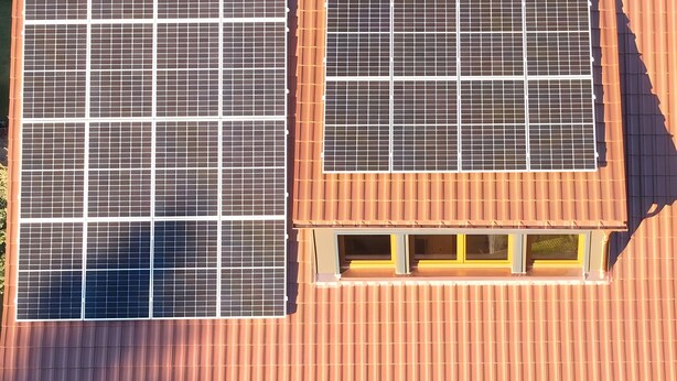 A building with two large solar panels on the roof and a small window with yellow trim. - Ground Floor Apartment '2 Rooms' with Outdoor Seating Area (St. Märgen)