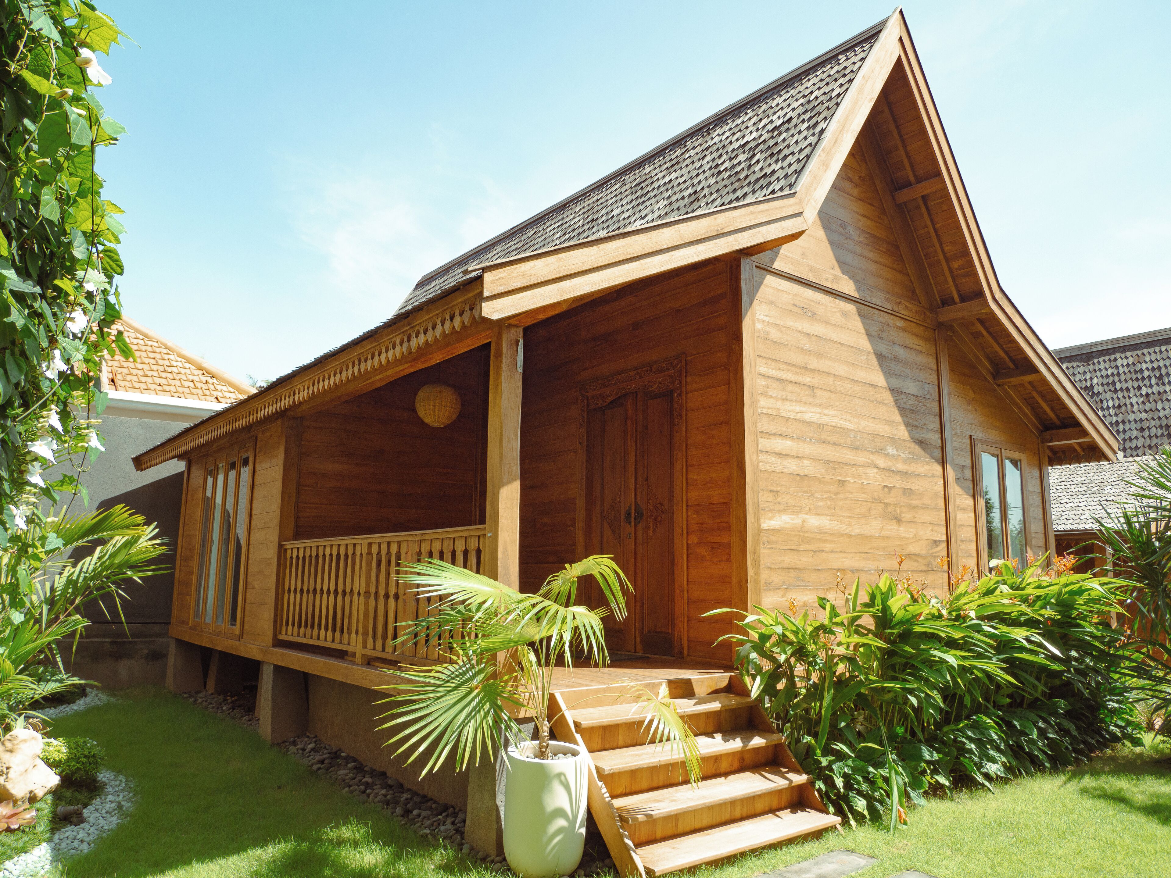 A wooden house with a porch, steps, and a garden.